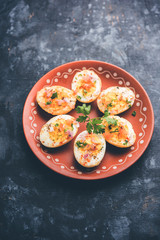 Fried hot boiled egg masala is a popular healthy breakfast or starter menu from India. With onion, coriander, black pepper, tomato and salt sprinkled over half of eggs