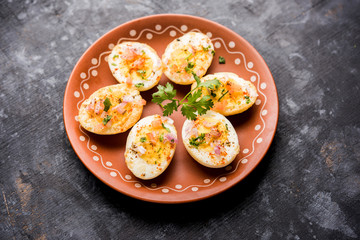 Fried hot boiled egg masala is a popular healthy breakfast or starter menu from India. With onion, coriander, black pepper, tomato and salt sprinkled over half of eggs