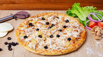 Pizza with cheese, olives and tomatoes on the table