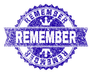 REMEMBER rosette stamp imprint with distress style. Designed with round rosette, ribbon and small crowns. Blue vector rubber print of REMEMBER label with grunge style.