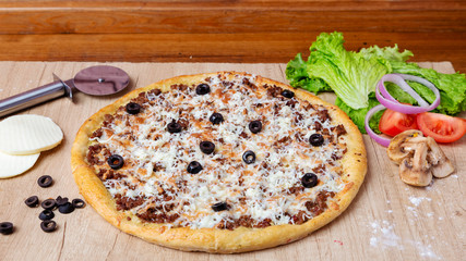 Pizza with cheese, olives and tomatoes on the table