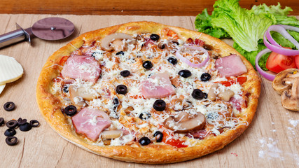 Pizza with cheese, olives and tomatoes on the table