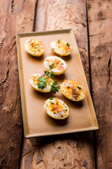 Fried hot boiled egg masala is a popular healthy breakfast or starter menu from India. With onion, coriander, black pepper, tomato and salt sprinkled over half of eggs