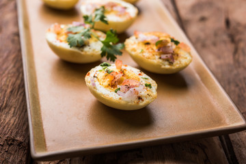 Fried hot boiled egg masala is a popular healthy breakfast or starter menu from India. With onion, coriander, black pepper, tomato and salt sprinkled over half of eggs