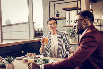 Charming brunette woman raising her hand with glass
