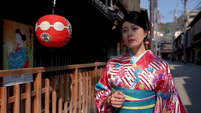 local girl lady walking through the wooden house with red lanterns hanging on roof under sunny day. young japanese female in beautiful traditional costume on kiyomizu sannenzaka street kyoto japan