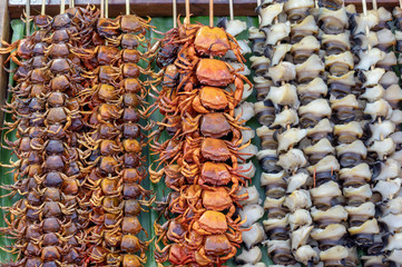 Small crab grilled and shells skewer with bamboo on a banana leaf, Arranged in a row.