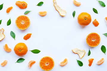 Frame of fresh orange citrus fruit with green leaves on white