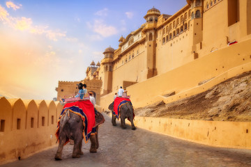 Naklejka premium Tourist couple enjoy elephant ride at the historic Amer Fort at sunset. Amer Fort is a UNESCO World heritage site at Jaipur Rajasthan India.