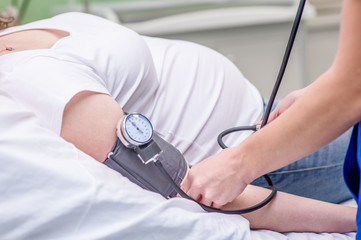 Close up pregnant woman having her blood pressure checked by the doctor