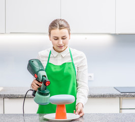 Confectioner decorates the cake with velour using the spray gun
