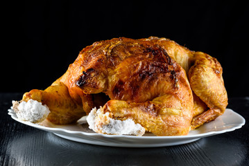 fried chicken whole, on a white plate on a wooden background