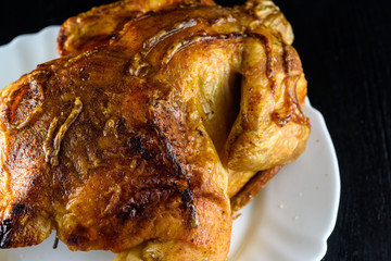 fried chicken whole, on a white plate on a wooden background
