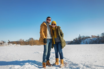 Happy young couple walking on winter sunny day. Full body, wide angle.