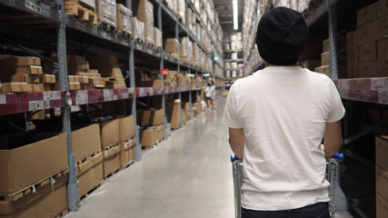 Warehouse large storage or cargo for distribution and man's back with shopping cart.