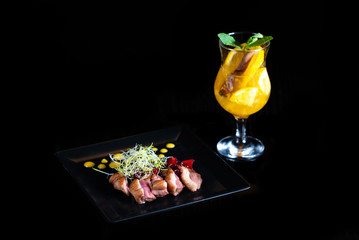 Winter warming drink with pieces of orange and spices on a black background