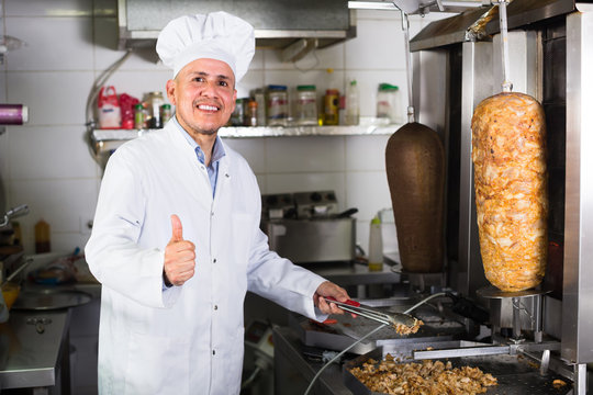 mature chef holding thumbs up on kitchen