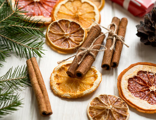 Obraz na płótnie Canvas Christmas decoration with dry orange, cinnamon sticks and trees brunches on white table. Dry citrus: orange, lemon, grapefruit.