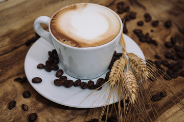Cappuccino con spiga di grano e chicchi di caffè su vassoio in legno | Cappuccino with wheat ear...