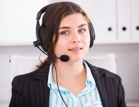 Young dispatcher woman is working at a computer and talking headset