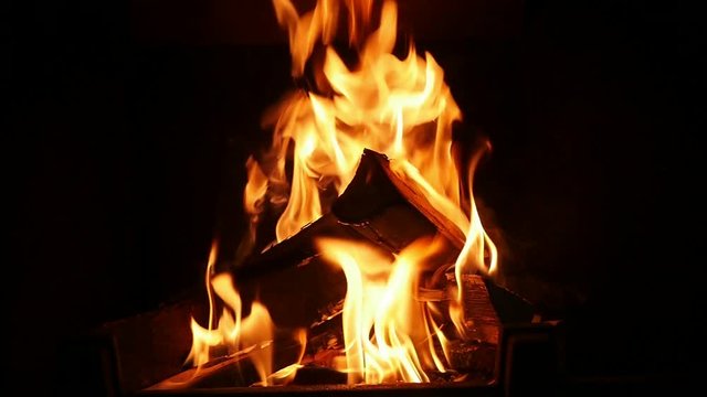 Live spurts of fire turning wooden logs into black ash in a fireplace  