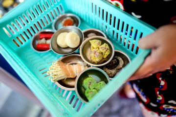 Dim sum in the basket, mixed dim sum in small stainless plate at street food stall in morning time.