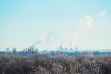 Modern landscape with factory pipes at distance from which smoke is polluting the air