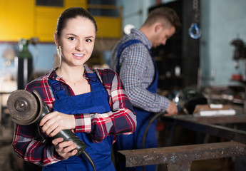 Female professional master is standing with circular saw