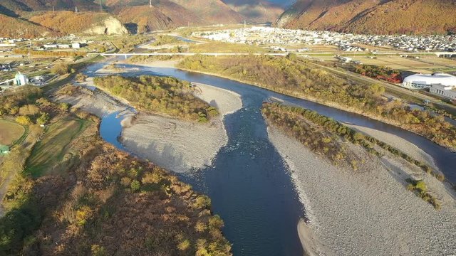 上空から川の水面へ近づいていき、川の流れに沿って撮影しました。ドローンの空撮です。天候は快晴で、撮影時期は秋冬頃です。