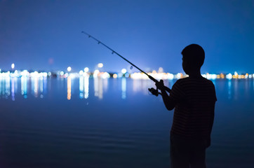 Silhouette fo boy fishing on night