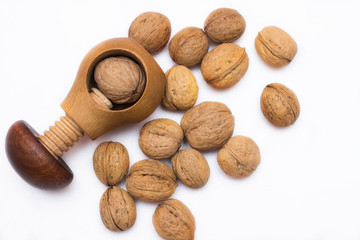 Wooden tool for crashing different nuts with several Greek nuts on white background