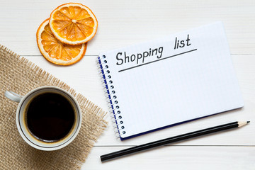 Shopping list on notepad on the white wooden table, copy space for your text