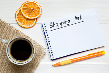 Shopping list on notepad on the white wooden table, copy space for your text