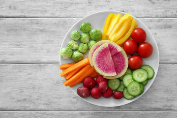 Plate with fresh vegetables on wooden table. Diet food