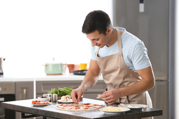 Fototapeta na wymiar Young man preparing tasty pizza at table