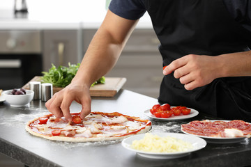 Obraz na płótnie Canvas Young man preparing tasty pizza at table