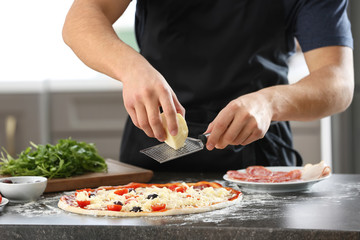 Obraz na płótnie Canvas Young man preparing tasty pizza at table