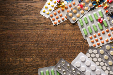 Different pills on wooden background