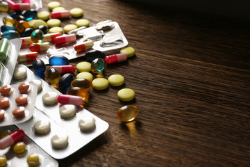 Different pills on wooden background