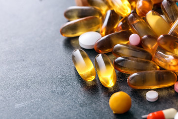 Different pills and capsules on grey background