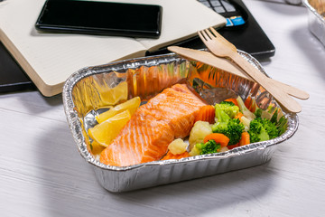 Healthy food delivery to workspace - containers, laptop, mobile phone, copy space