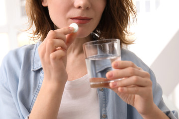 Young woman taking pill, indoors
