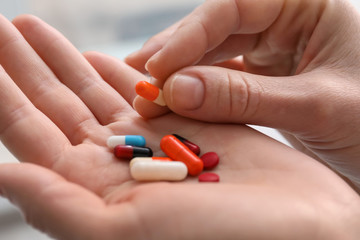 Young woman holding different pills, closeup