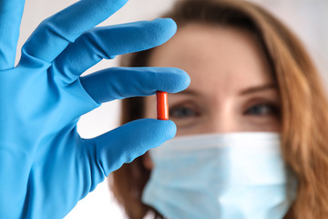 Young doctor holding pill, closeup