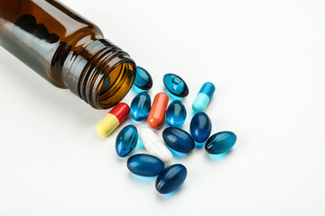 Glass bottle with pills on white background