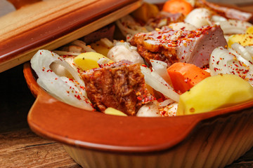 Homemade smoked meat and vegetables ready for cooking in ceramic bowl. Sweet and plain potato, carrot, champignon mushrooms garlic and onion.