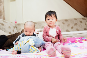 Closeup of happy little child playing over the bed in a relaxed morning with her little baby sister.