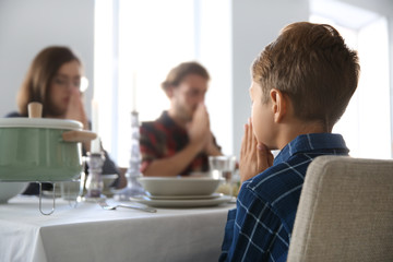 Family praying before meal at home