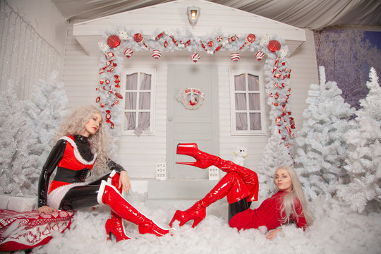 Two Bad Santa's Girlfriends In Latex Costumes Play In The Front Yard Of Their House At Christmas