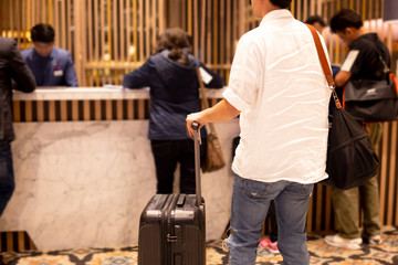 Man holding passport with suitcase waiting to checking in at hotel.